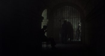 Movie still from “Midnight Express” (1978), directed by Alan Parker – A person sitting in a chair in a dark room; Wide shot, High angle