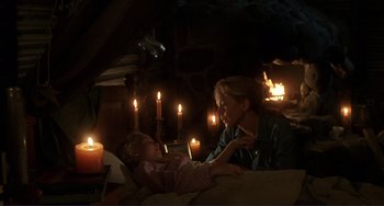 Movie still from “Mighty Joe Young” (1998), directed by Ron Underwood – A woman and a little girl sitting on a bed with lit candles; Medium shot, High angle