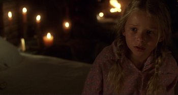 Movie still from “Mighty Joe Young” (1998), directed by Ron Underwood – A woman in a pink shirt is in front of candles; Close Up shot, Over the shoulder angle