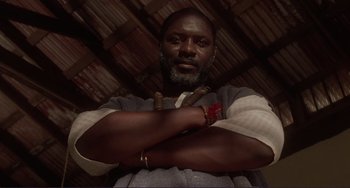 Movie still from “Mighty Joe Young” (1998), directed by Ron Underwood – A man with his arms crossed in front of a ceiling; Close Up shot, Low angle