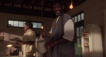 Movie still from “Mighty Joe Young” (1998), directed by Ron Underwood – A man holding a bag in a room with lights; Medium shot, Low angle