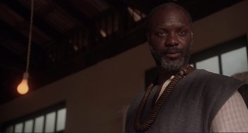 Movie still from “Mighty Joe Young” (1998), directed by Ron Underwood – A man with a beard wearing a necklace; Close Up shot, Low angle