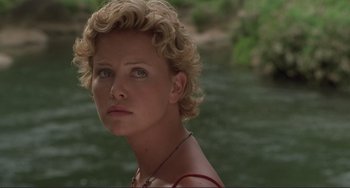Movie still from “Mighty Joe Young” (1998), directed by Ron Underwood – A person wearing a necklace near a body of water; Close Up shot, Over the shoulder angle