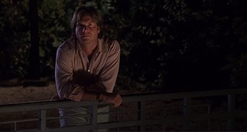 Movie still from “Mighty Joe Young” (1998), directed by Ron Underwood – A man leaning on a railing in the dark; Medium shot, Low angle