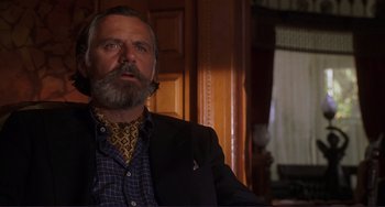 Movie still from “Mighty Joe Young” (1998), directed by Ron Underwood – A man sitting in a chair in a room; Close Up shot, Low angle