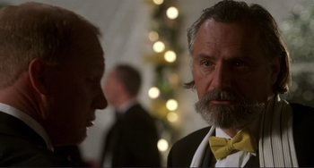 Movie still from “Mighty Joe Young” (1998), directed by Ron Underwood – A man with a beard and a bow tie is talking to another man in a suit; Close Up shot, Over the shoulder angle
