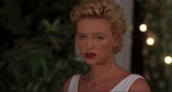 Movie still from “Mighty Joe Young” (1998), directed by Ron Underwood – A woman with blonde hair and red lipstick looking at the camera; Close Up shot, Over the shoulder angle