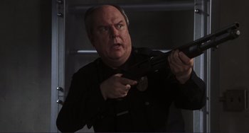Movie still from “Mighty Joe Young” (1998), directed by Ron Underwood – A man holding a gun in a room; Medium shot, Low angle