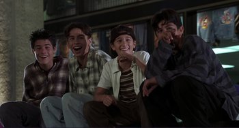 Movie still from “Mighty Joe Young” (1998), directed by Ron Underwood – A group of young men sitting next to each other; Medium shot, Low angle