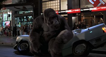 Movie still from “Mighty Joe Young” (1998), directed by Ron Underwood – A gorilla sitting on the hood of a car; Wide shot, Low angle