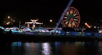 Movie still from “Mighty Joe Young” (1998), directed by Ron Underwood – A view of a ferris wheel at night from the water; Extreme Wide shot, High angle