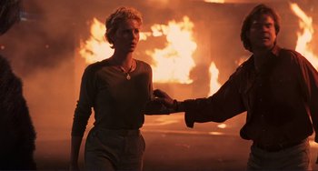 Movie still from “Mighty Joe Young” (1998), directed by Ron Underwood – A woman is being held by a man in front of a fire; Medium shot, Low angle