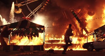 Movie still from “Mighty Joe Young” (1998), directed by Ron Underwood – A man walking in front of an amusement park fire; Wide shot, Low angle
