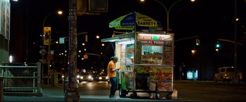 Movie still from “Mike and Dave Need Wedding Dates” (2016), directed by Jake Szymanski – A man standing in front of a food stand on the side of the road; Wide shot, Low angle