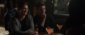 Movie still from “Mike and Dave Need Wedding Dates” (2016), directed by Jake Szymanski – Two young men sitting at a table with drinks; Medium shot, Over the shoulder angle