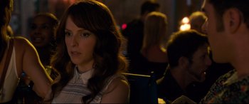 Movie still from “Mike and Dave Need Wedding Dates” (2016), directed by Jake Szymanski – A woman sitting at a table in front of other people; Close Up shot, Over the shoulder angle