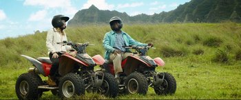 Movie still from “Mike and Dave Need Wedding Dates” (2016), directed by Jake Szymanski – A man sitting on the back of a four - wheelers; Wide shot, Over the shoulder angle