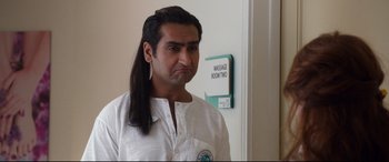 Movie still from “Mike and Dave Need Wedding Dates” (2016), directed by Jake Szymanski – A man with long black hair is standing in front of a sign; Close Up shot, Over the shoulder angle