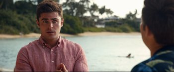 Movie still from “Mike and Dave Need Wedding Dates” (2016), directed by Jake Szymanski – A man in a red shirt is by the water; Close Up shot, Over the shoulder angle