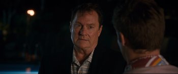 Movie still from “Mike and Dave Need Wedding Dates” (2016), directed by Jake Szymanski – An older man in a black suit and striped shirt; Close Up shot, Over the shoulder angle