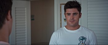 Movie still from “Mike and Dave Need Wedding Dates” (2016), directed by Jake Szymanski – A man in a white t - shirt is standing in a room; Close Up shot, Over the shoulder angle