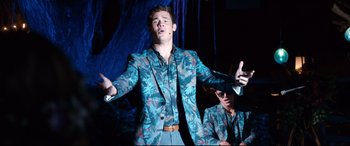 Movie still from “Mike and Dave Need Wedding Dates” (2016), directed by Jake Szymanski – A man wearing a suit and tie and a microphone; Medium shot, Low angle