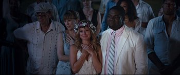 Movie still from “Mike and Dave Need Wedding Dates” (2016), directed by Jake Szymanski – A woman in a flower crown is standing next to a man in a suit and tie; Medium shot, Over the shoulder angle