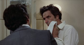 Movie still from “Mikey and Nicky” (1976), directed by Elaine May – A man in a white dress shirt is looking at himself in the mirror; Close Up shot, Over the shoulder angle