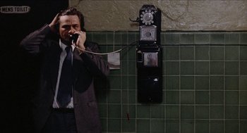 Movie still from “Mikey and Nicky” (1976), directed by Elaine May – A man talking on a phone next to a wall; Medium shot, High angle