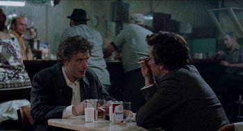 Movie still from “Mikey and Nicky” (1976), directed by Elaine May – Two men sitting at a table in front of each other; Medium shot, Over the shoulder angle