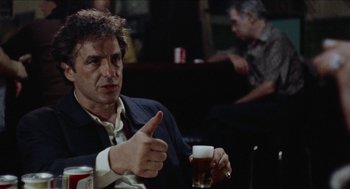 Movie still from “Mikey and Nicky” (1976), directed by Elaine May – A man holding a glass of beer and pointing at something; Medium shot, Low angle
