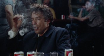 Movie still from “Mikey and Nicky” (1976), directed by Elaine May – A man sitting at a table smoking a cigarette; Close Up shot, Low angle