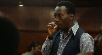 Movie still from “Mikey and Nicky” (1976), directed by Elaine May – A black man eating something while standing in front of a crowd; Close Up shot, Low angle