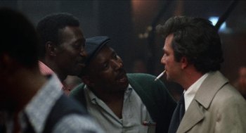 Movie still from “Mikey and Nicky” (1976), directed by Elaine May – A group of men standing next to each other in a room; Close Up shot, Over the shoulder angle