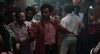 Movie still from “Mikey and Nicky” (1976), directed by Elaine May – A group of men standing around in a room; Medium shot, Low angle