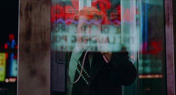 Movie still from “Mikey and Nicky” (1976), directed by Elaine May – A man talking on a phone in front of a store window; Medium shot, Over the shoulder angle