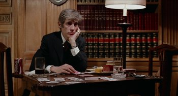 Movie still from “Mikey and Nicky” (1976), directed by Elaine May – A man sitting at a table in front of cards; Medium shot, Over the shoulder angle