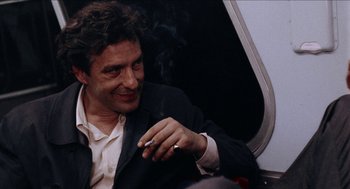 Movie still from “Mikey and Nicky” (1976), directed by Elaine May – A man smoking a cigarette while sitting on a train; Close Up shot, Over the shoulder angle