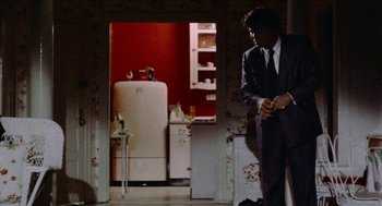 Movie still from “Mikey and Nicky” (1976), directed by Elaine May – A man in a suit standing in front of an old refrigerator; Medium shot, Over the shoulder angle