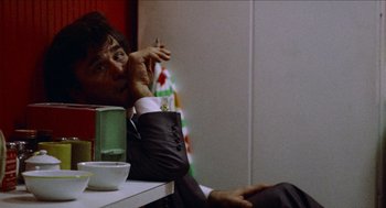 Movie still from “Mikey and Nicky” (1976), directed by Elaine May – A man sitting at a table smoking a cigarette; Close Up shot, Over the shoulder angle