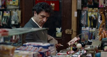 Movie still from “Mikey and Nicky” (1976), directed by Elaine May – A man in a suit is looking at a box of candy; Medium shot, Over the shoulder angle