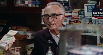Movie still from “Mikey and Nicky” (1976), directed by Elaine May – An older man wearing glasses sitting in front of a counter; Close Up shot, Low angle