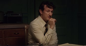 Movie still from “Milk” (2008), directed by Gus Van Sant – A man sitting at a table with his hand under his chin; Medium shot, Low angle