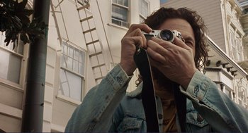 Movie still from “Milk” (2008), directed by Gus Van Sant – A man taking a picture with a camera; Close Up shot, Low angle