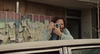 Movie still from “Milk” (2008), directed by Gus Van Sant – A man taking a picture of himself with a camera; Medium shot, Low angle