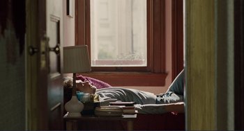 Movie still from “Milk” (2008), directed by Gus Van Sant – A person laying on a bed near a window; Wide shot, High angle