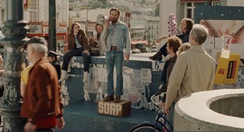 Movie still from “Milk” (2008), directed by Gus Van Sant – A group of people sitting on top of a platform; Wide shot, Low angle