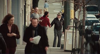 Movie still from “Milk” (2008), directed by Gus Van Sant – A group of people walking down a sidewalk; Wide shot, Over the shoulder angle