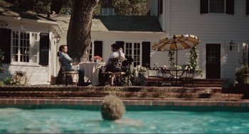 Movie still from “Milk” (2008), directed by Gus Van Sant – Two people sitting at a table in a swimming pool; Extreme Wide shot, Over the shoulder angle