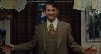 Movie still from “Milk” (2008), directed by Gus Van Sant – A man in a suit and tie smiling for the camera; Medium shot, Over the shoulder angle